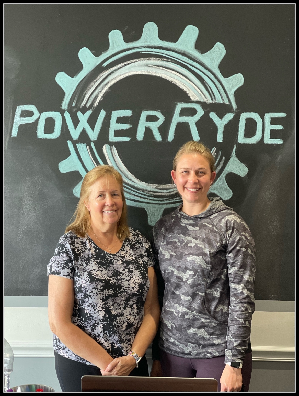 Jane Ceddia and Erin Giblin in front of PowerRyde chalk logo